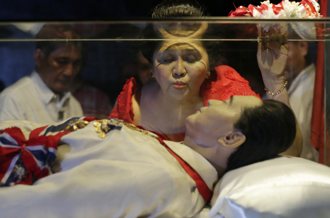 Imelda Marcos kisses the glass enclosure holding the preserved body of her late husband, Ferdinand [EPA]