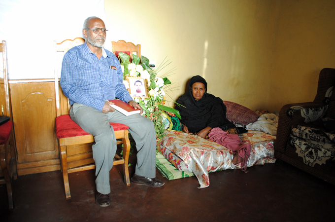 Lalango Hayesso and Tirfe Welde Senbet, Hanna's parents, mourn beside her photograph [Jacey Fortin/Al Jazeera]