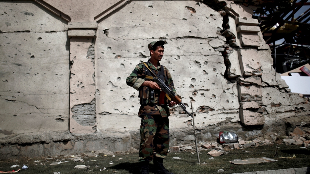 A member of the Afghan security force stands in front of a damaged building a day after attacks outside the Afghan parliament in Kabul [REUTERS]