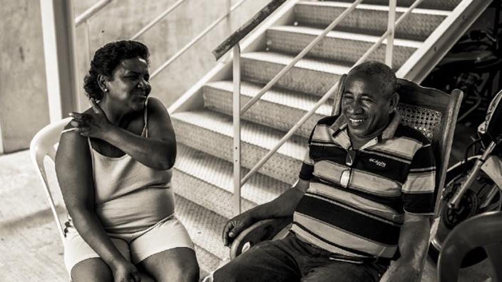 Belkis, left, and Saturnino sit outside their new apartment in Ciudad Zamora [Alejandro Cegarra/Al Jazeera]
