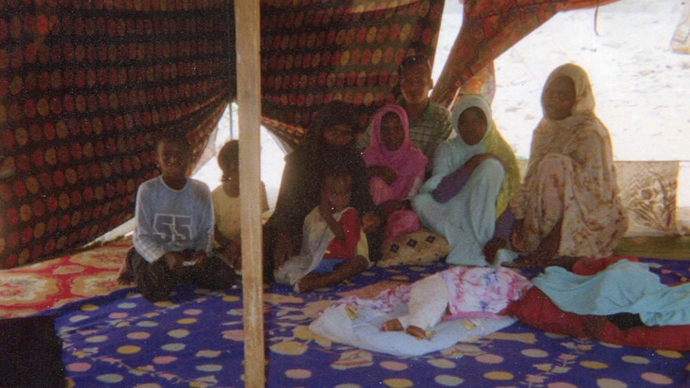 A family of freed slaves sit on the floor of a tent as they share their story [Jacinda Townsend/Al Jazeera]