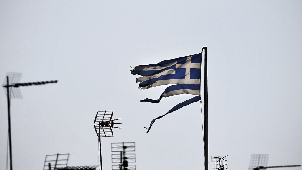 A frayed Greek national flag flutters among antennas atop a building in central Athens, Greece [REUTERS]