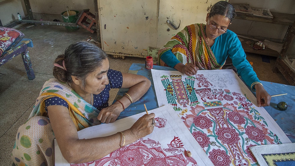 Maithil women paint traditional art on to canvasses in a workshop inside the Janakpur Women's Development Centre, where up to 40 Maithil women work [Omar Havana/Al Jazeera]