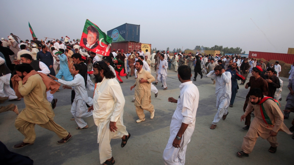 Supporters of Pakistani opposition leader Imran Khan run from tear gas as clashes begin between police and protesters in Swabi