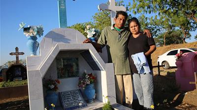 Margarita Mendoza and her husband stand beside the grave of their son, who was killed last year during the crackdown [Chris Kenning/Al Jazeera] 