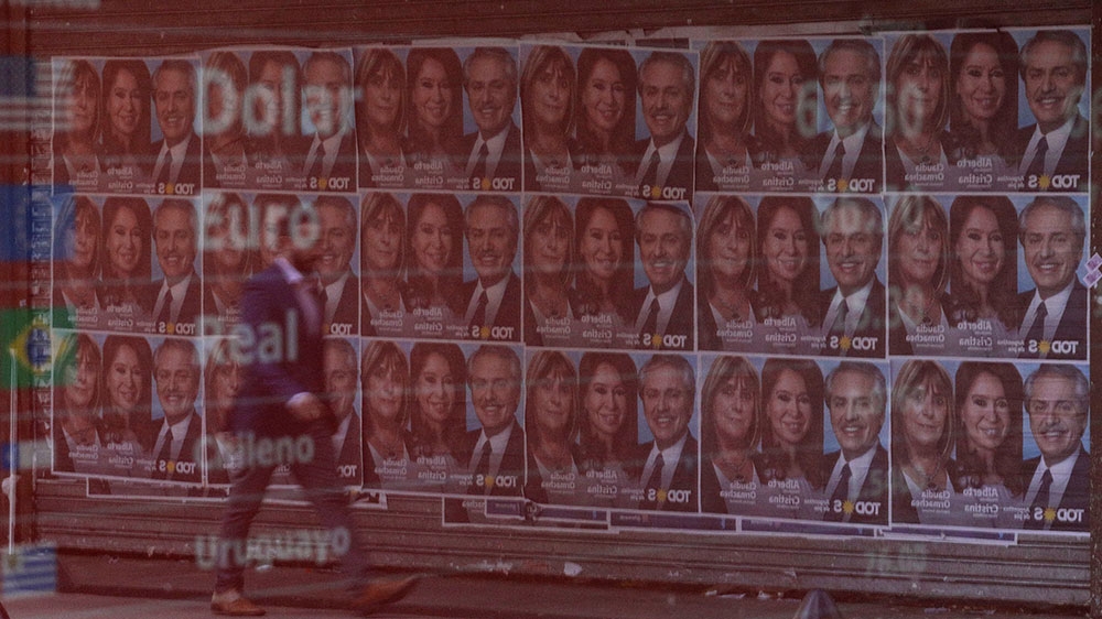 Campaign posters for opposition presidential candidate Alberto Fernandez are reflected in an electronic board that shows currency exchange in Buenos Aires’s financial district