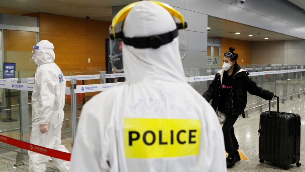 Police officer in a protective suit keeps watch on inbound travellers at Shanghai Pudong International Airport following a global outbreak of coronavirus disease