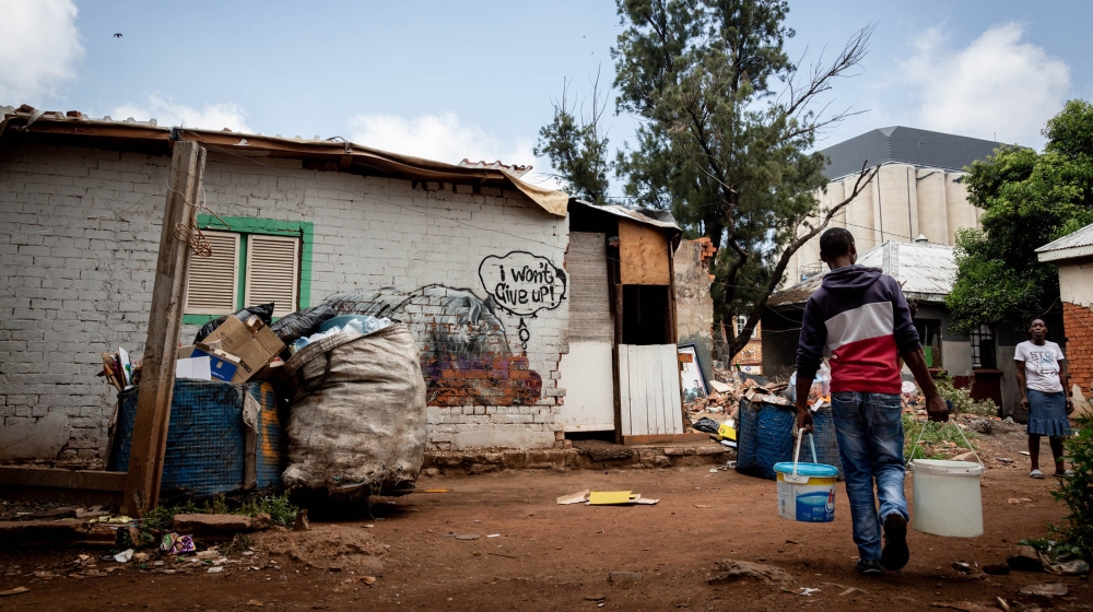 A man carries water in buckets collected from communal taps in Bekezela