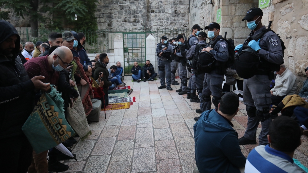 Israeli police stand guard in front of the mosque doors as Palestinian Muslims gather to perform Eid al-Fitr prayer at Al-Aqsa Mosque, which was closed as a precaution against the coronavirus