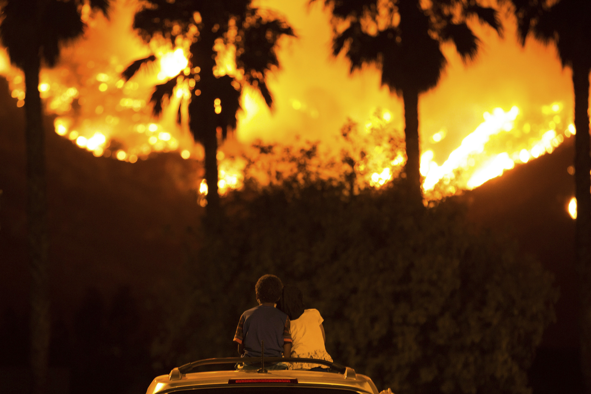 Six-year-old King Bass (left) sits and watches the Holy Fire burn from on top of his parents’ car as his five-year-old sister Princess rests her head on his shoulder on August 9, 2018 in Lake Elsinore, California