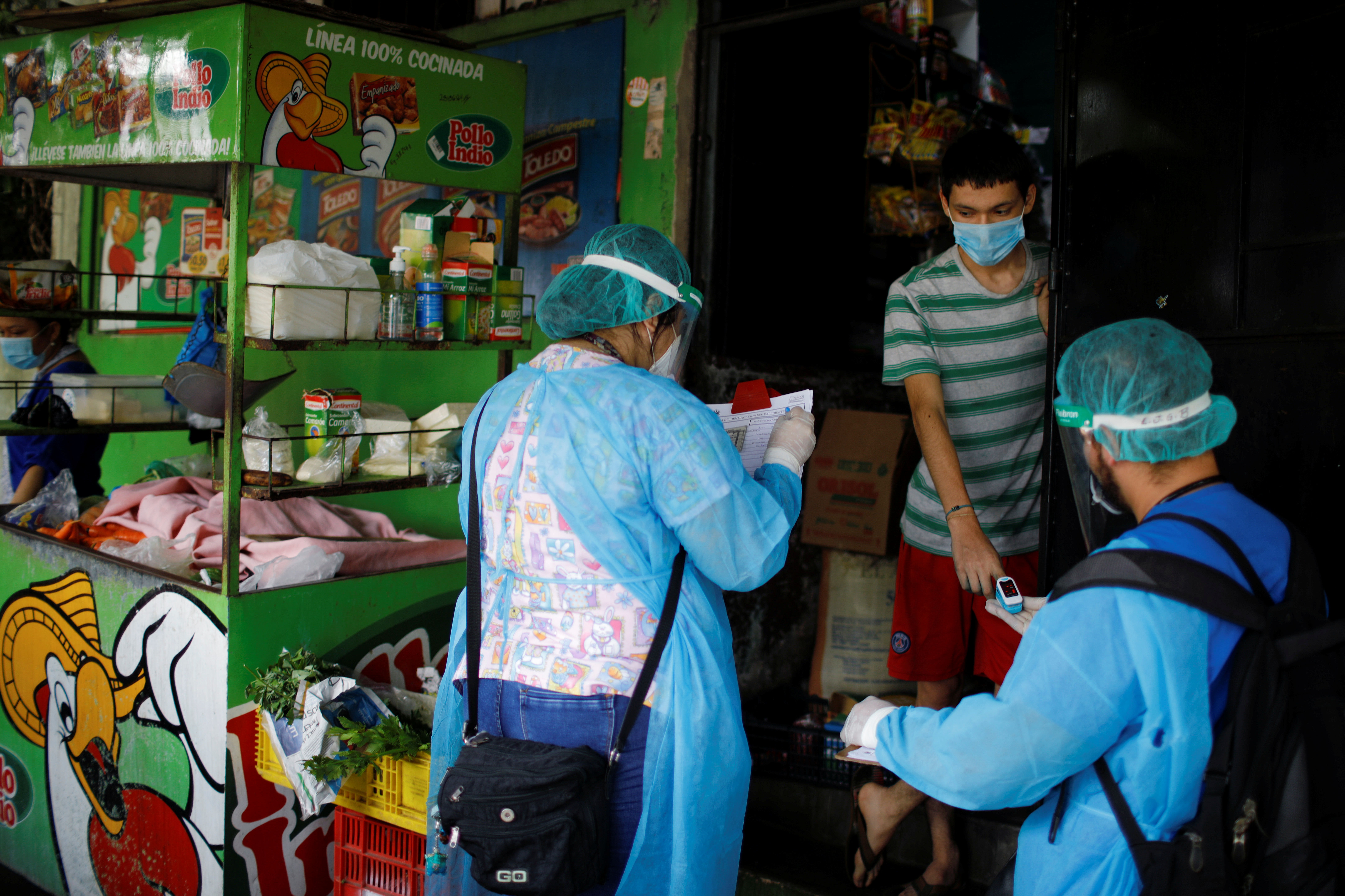 Healthcare workers examine a resident during a house-to-house medical campaign as they conduct contact tracing amid the coronavirus disease outbreak in El Salvador [Reuters]