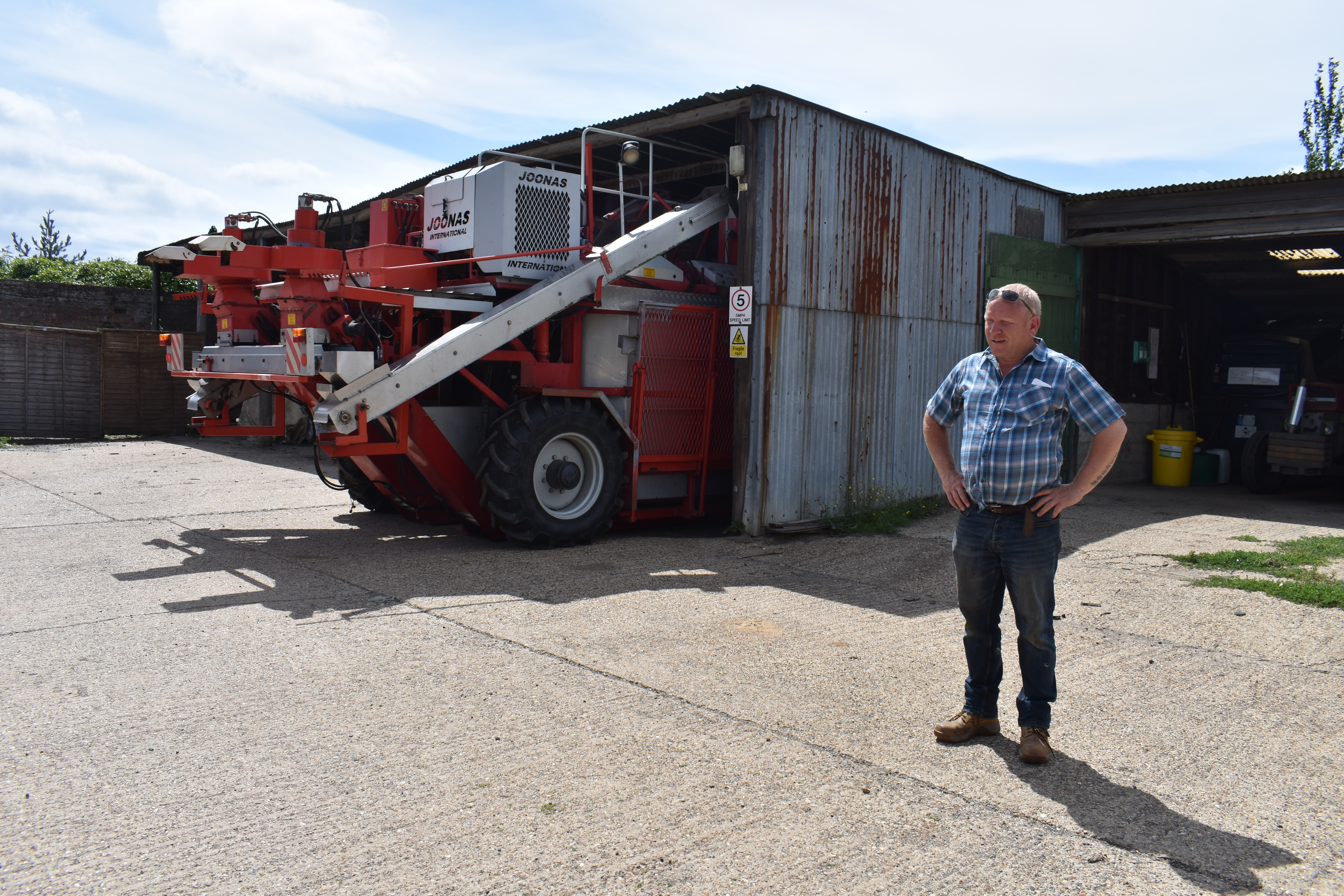 A farm manager stands next to a tractor at a strawberry farm in Kent