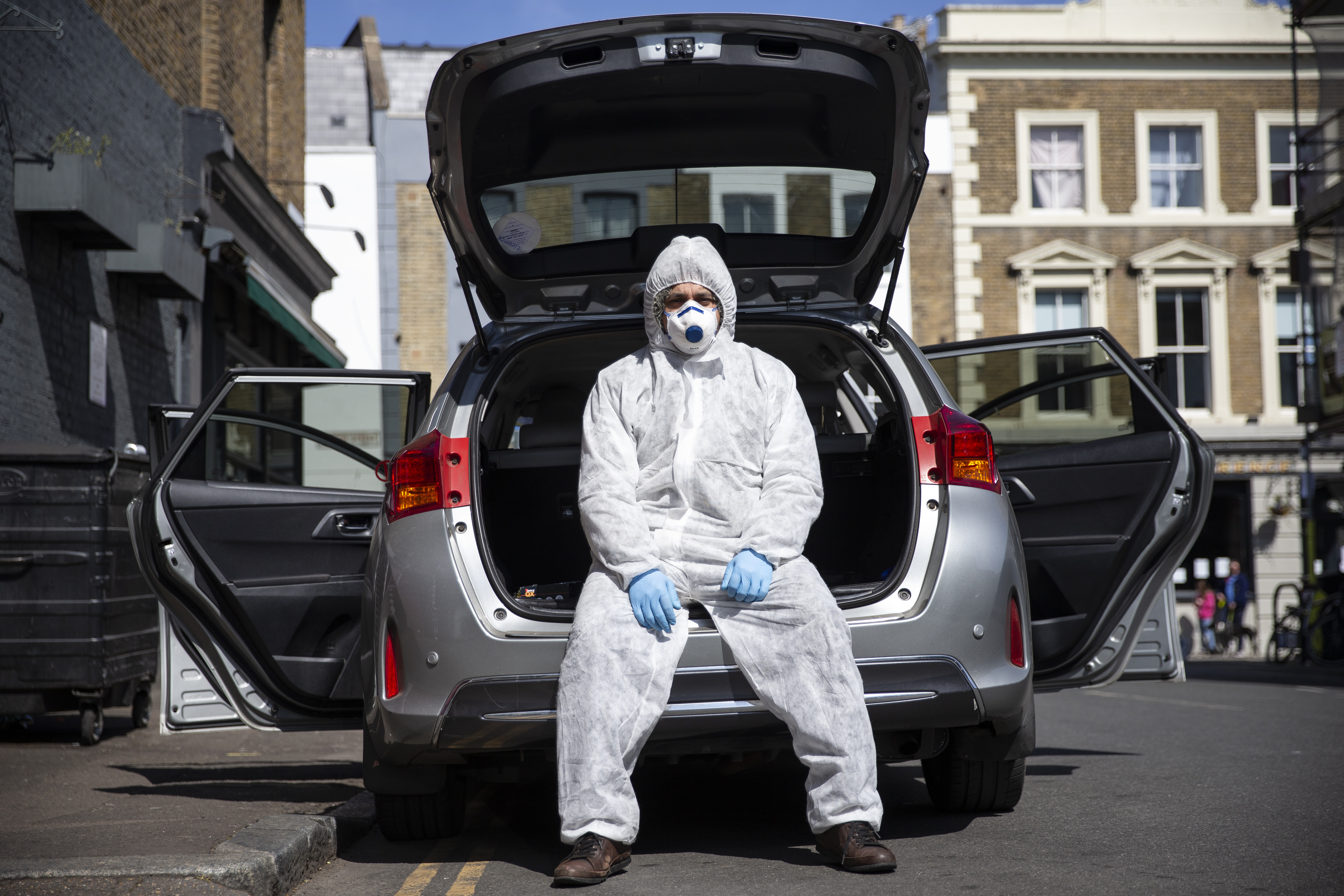 Uber driver Yasar Gorur wears personal protective equipment while cleaning his vehicle on April 14, 2020 in London, United Kingdom. Gorur says he wipes down the seats in his car every 2-3 trips and wears personal protective equipment whenever he drives [Hollie Adams/Getty Images]