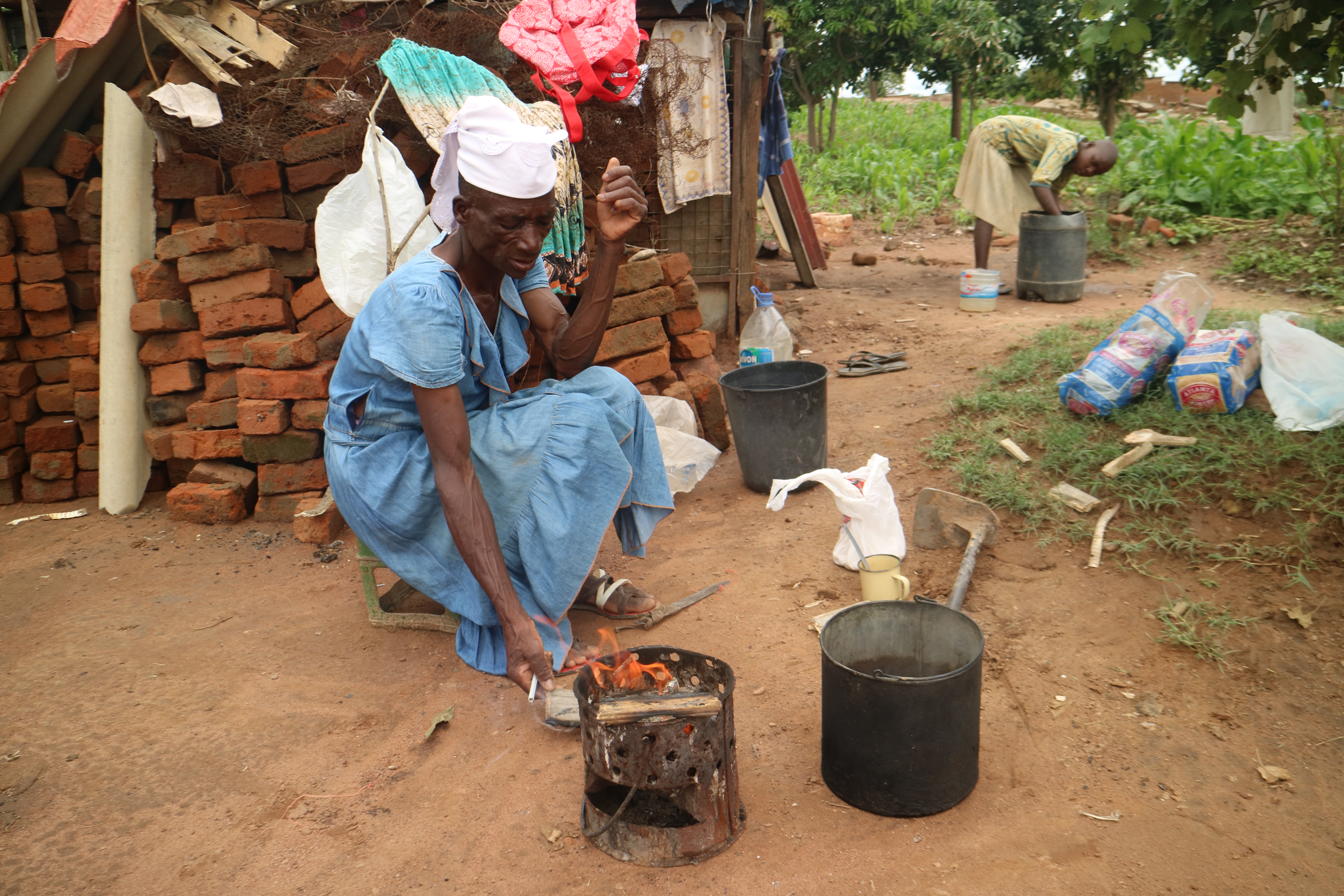 Chengeto Tapfuma, 59, boils water for tea outside the temporary shack she now shares with her four grandchildren. Their home in Budiriro 5, a suburb of Harare, was demolished by bulldozers in December after a court ruled that the residents had built their homes here illegally [Derick Matsengarwodzi/Al Jazeera]