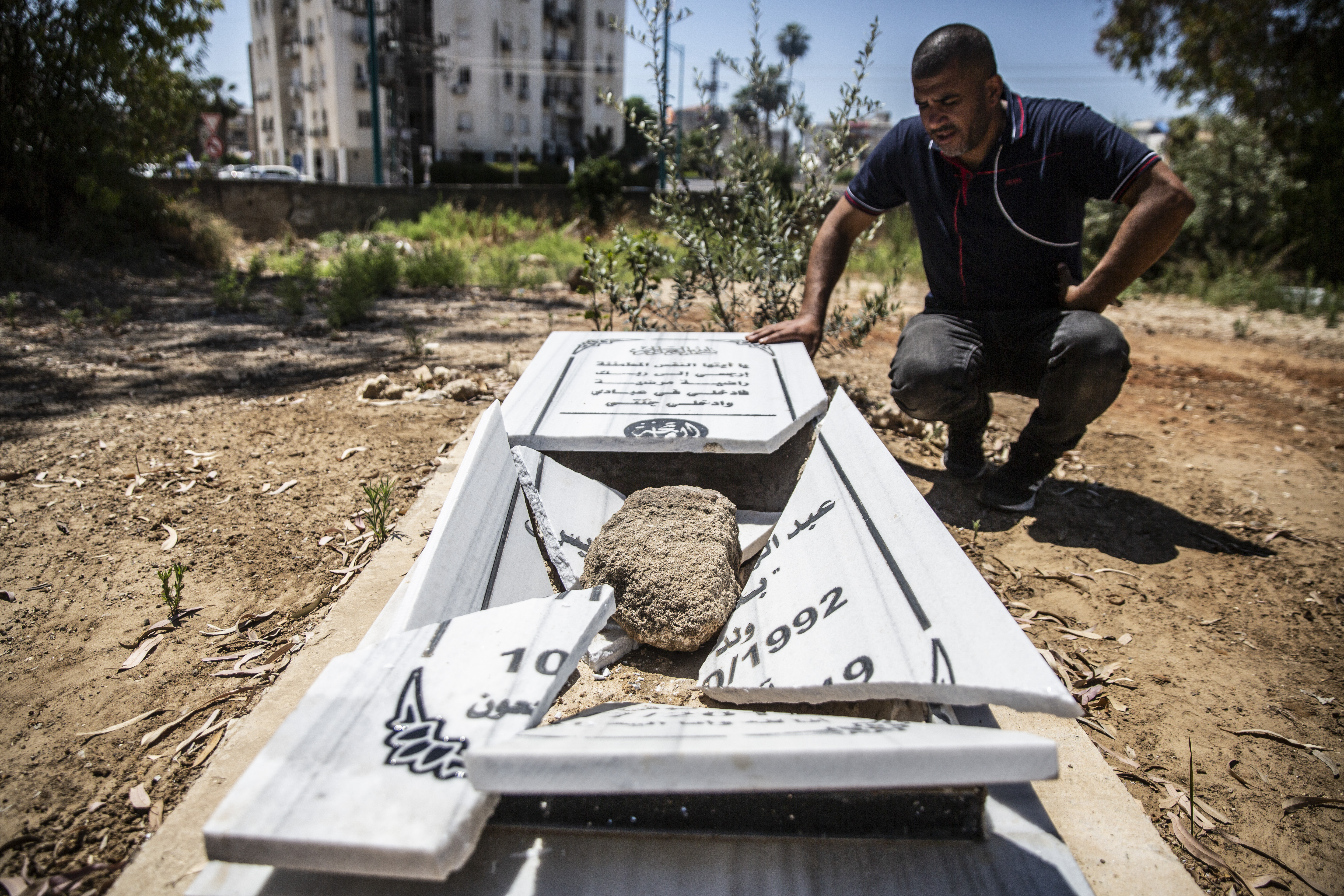 Jamal Abu Kasher, a resident of Lydd, looks at one of the several vandalised graves in a Muslim cemetery on May 14, 2021