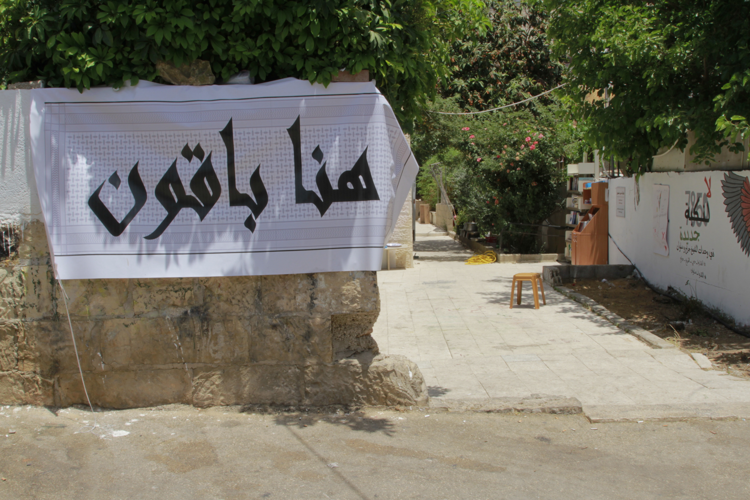A poster in Sheikh Jarrah says ‘here we shall remain’ [Al Jazeera]
