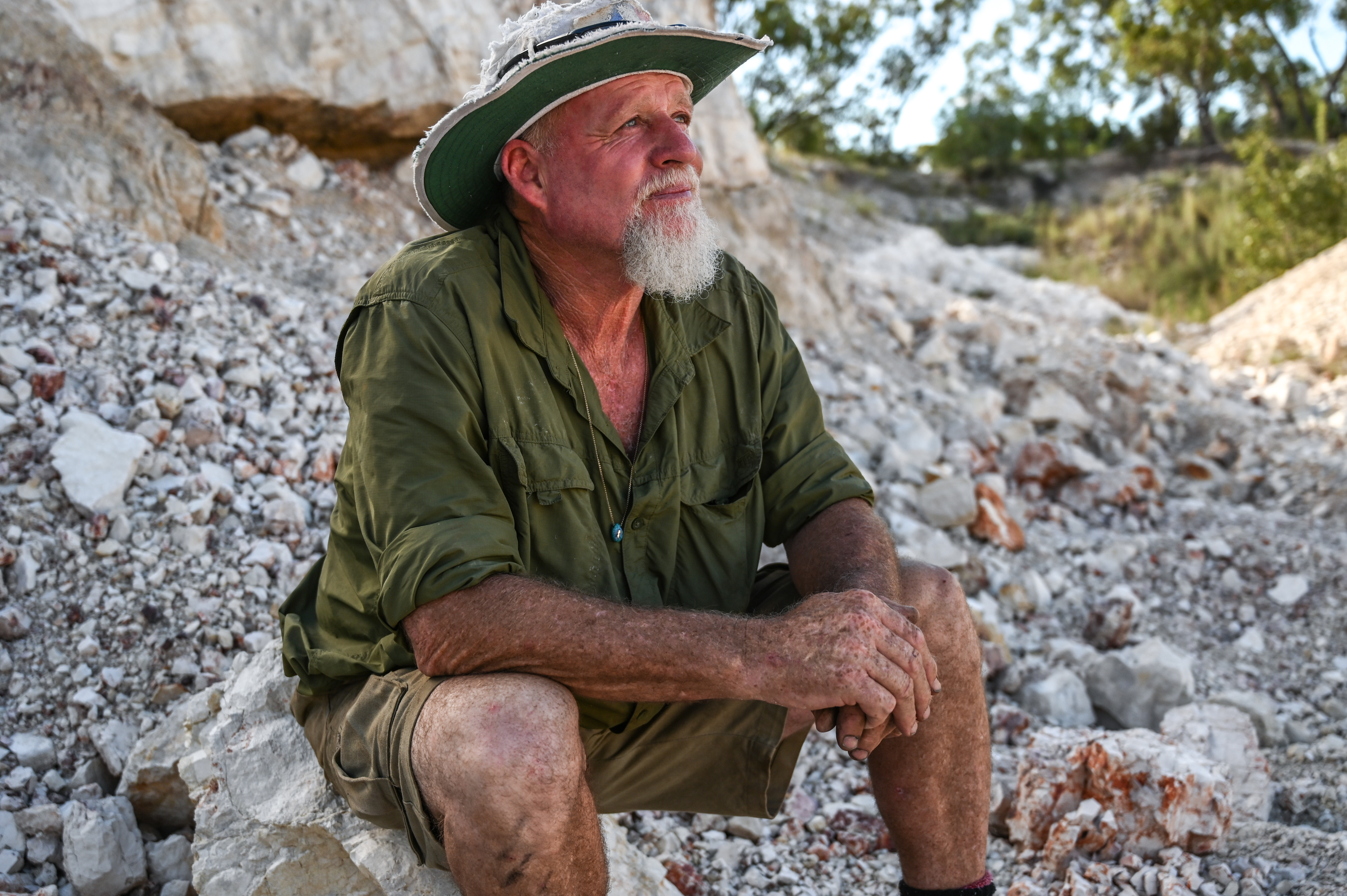 A photo of Pete Cooke sitting on rocks.