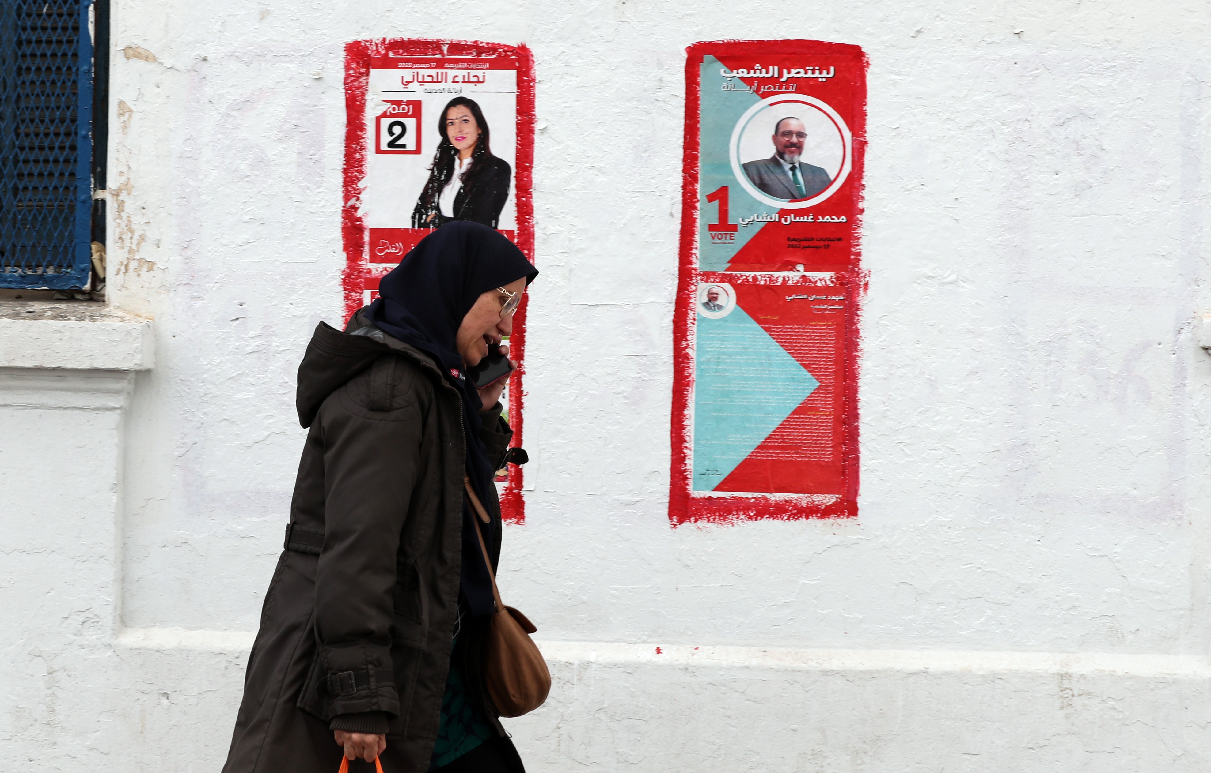 A woman walks past campaign posters ahead of the parliamentary elections in Tunis [Mohamed Messara/EPA-EFE]