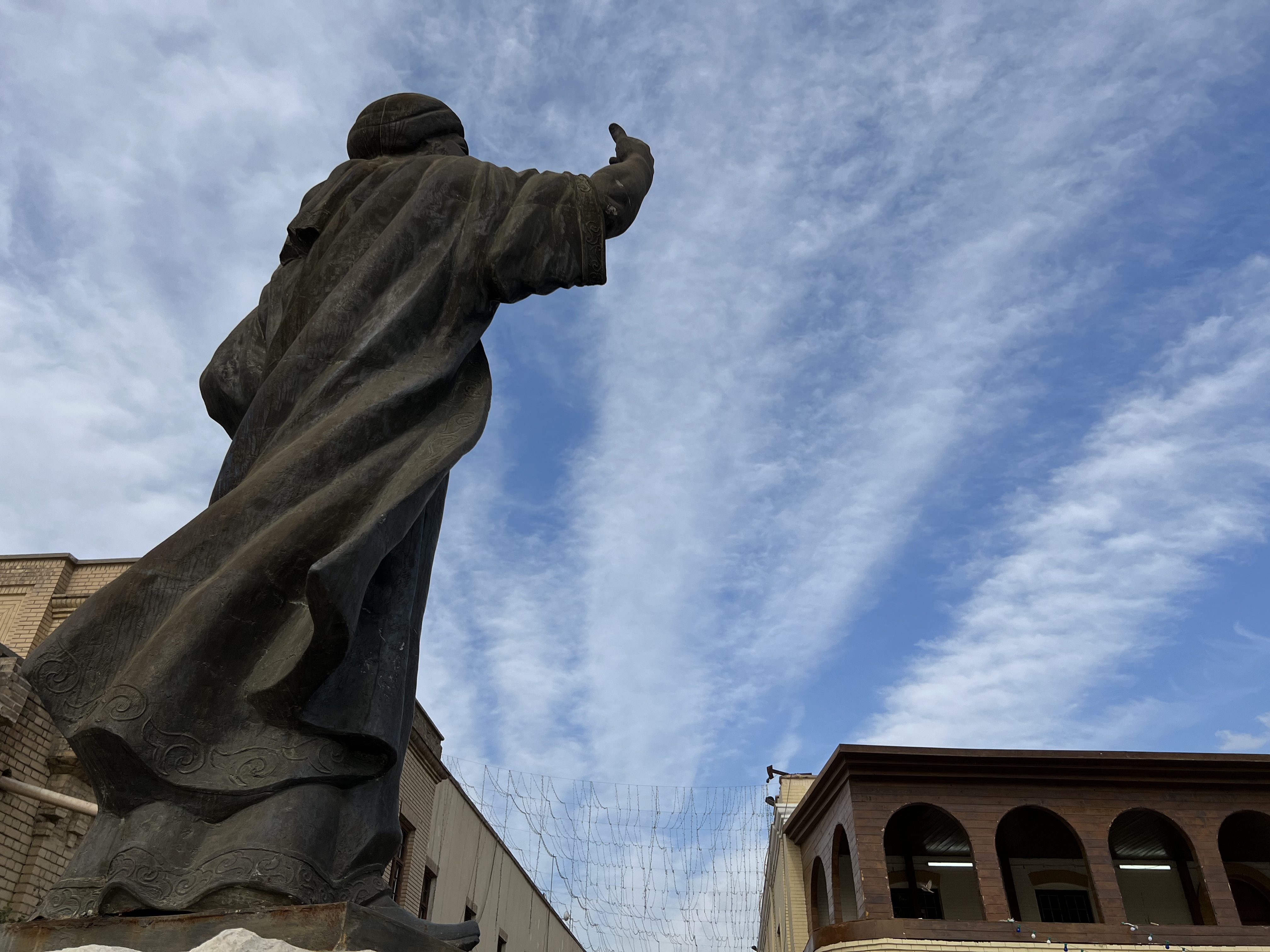 Statue in Mutannabi Street from behind, image shot from below looking up at a blue sky.