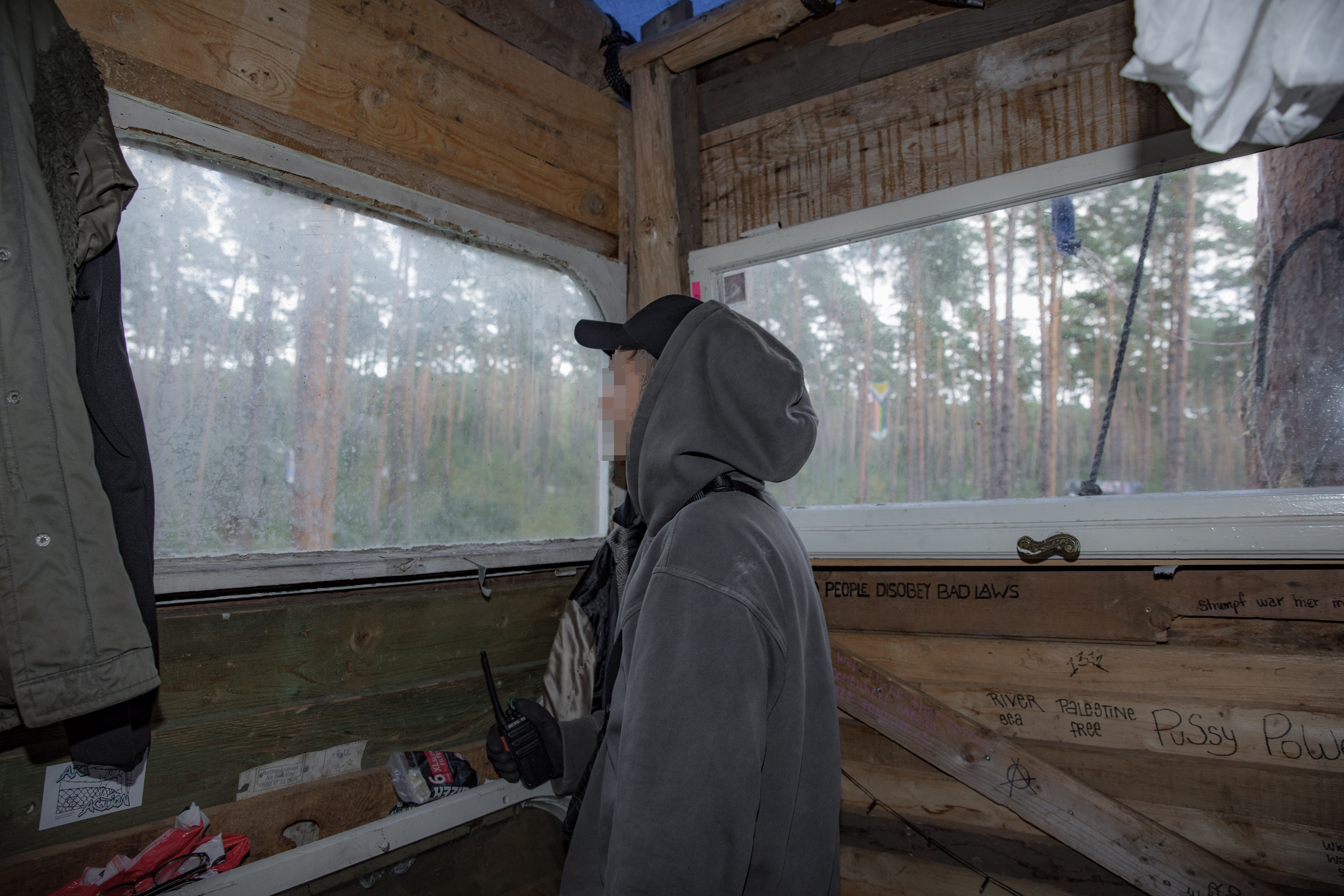 A forest defender in a treehouse looking out of the window, ready to act if an eviction starts