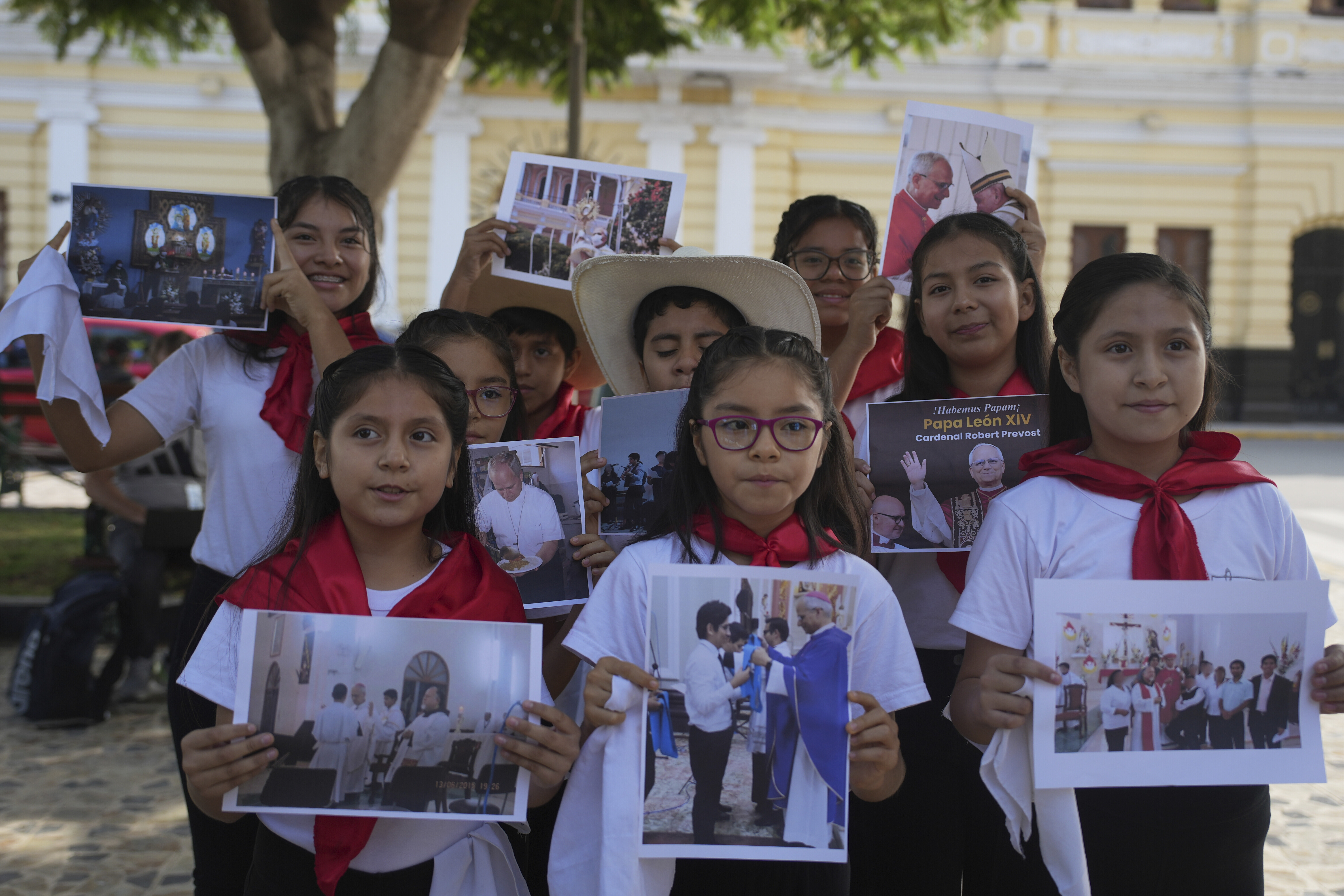 Members of a children’s choir display photos of newly elected Pope Leo XIV on May 9