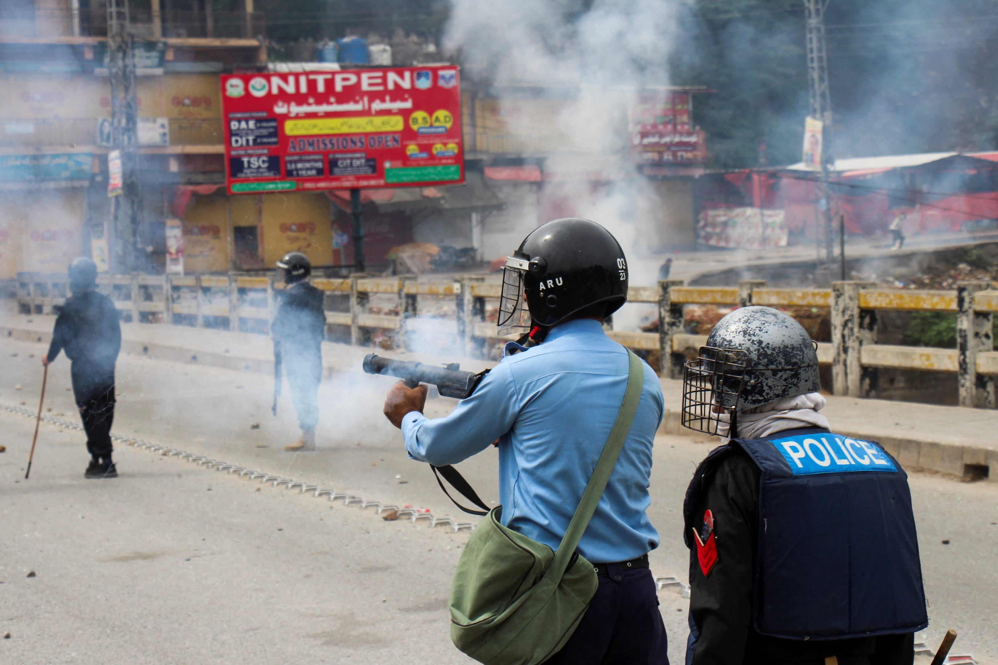A police officer fires tear gas to disperse the protesters of the Awami Action Committee during a protest following a shutter-down strike in Muzaffarabad, the capital of Pakistan-administered Kashmir, Pakistan October 1, 2025. REUTERS/Naseer ud Din