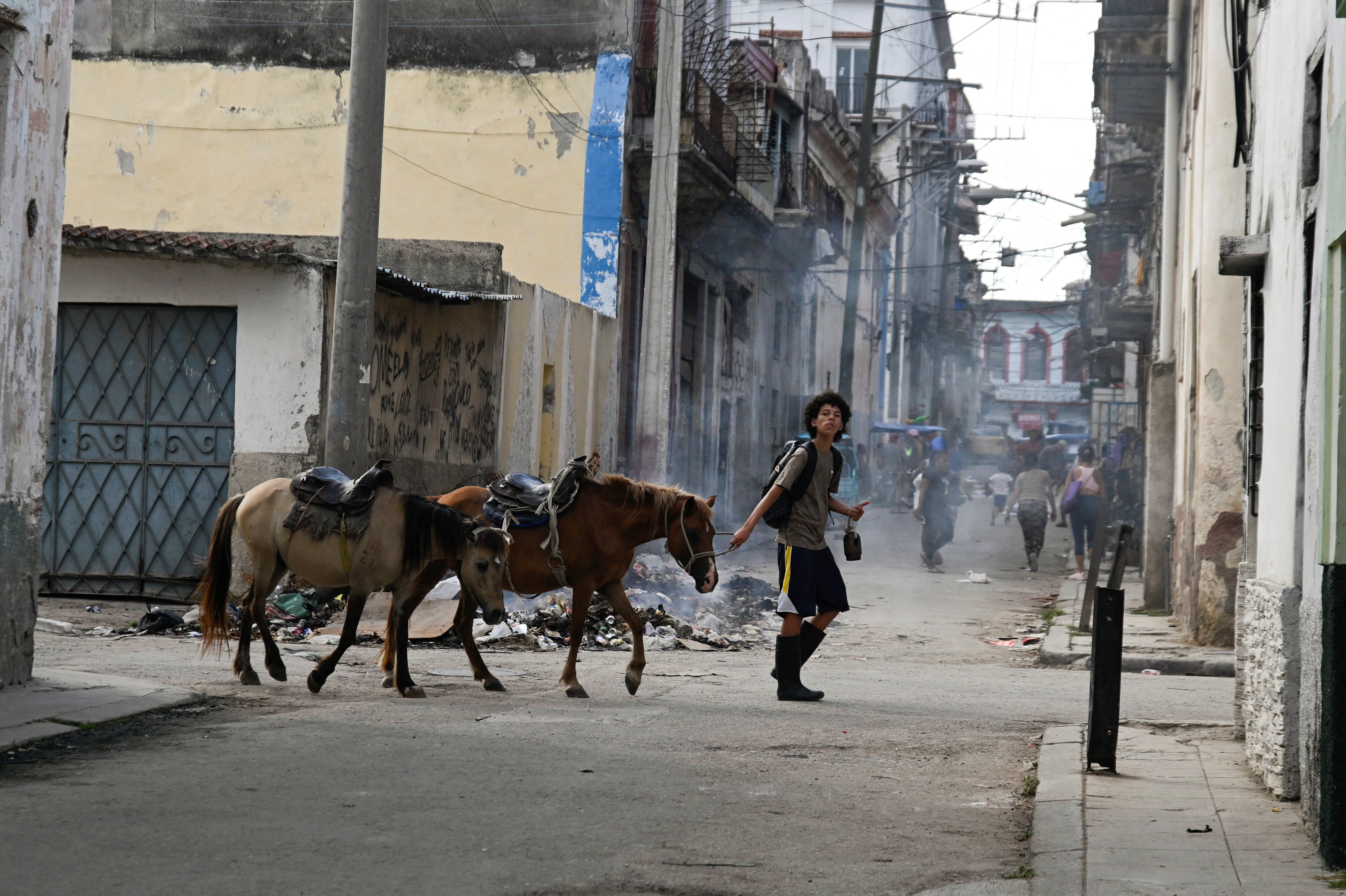 A boy leads two horses as he walks by a burning pile of garbage after Cuba's President Miguel Diaz-Canel announced that Cuba has opened talks with the U.S. government as an oil blockade imposed by U.S. President Donald Trump pushes the Communist-run nation deeper into economic crisis in Havana, Cuba March 13, 2026. REUTERS/Norlys Perez