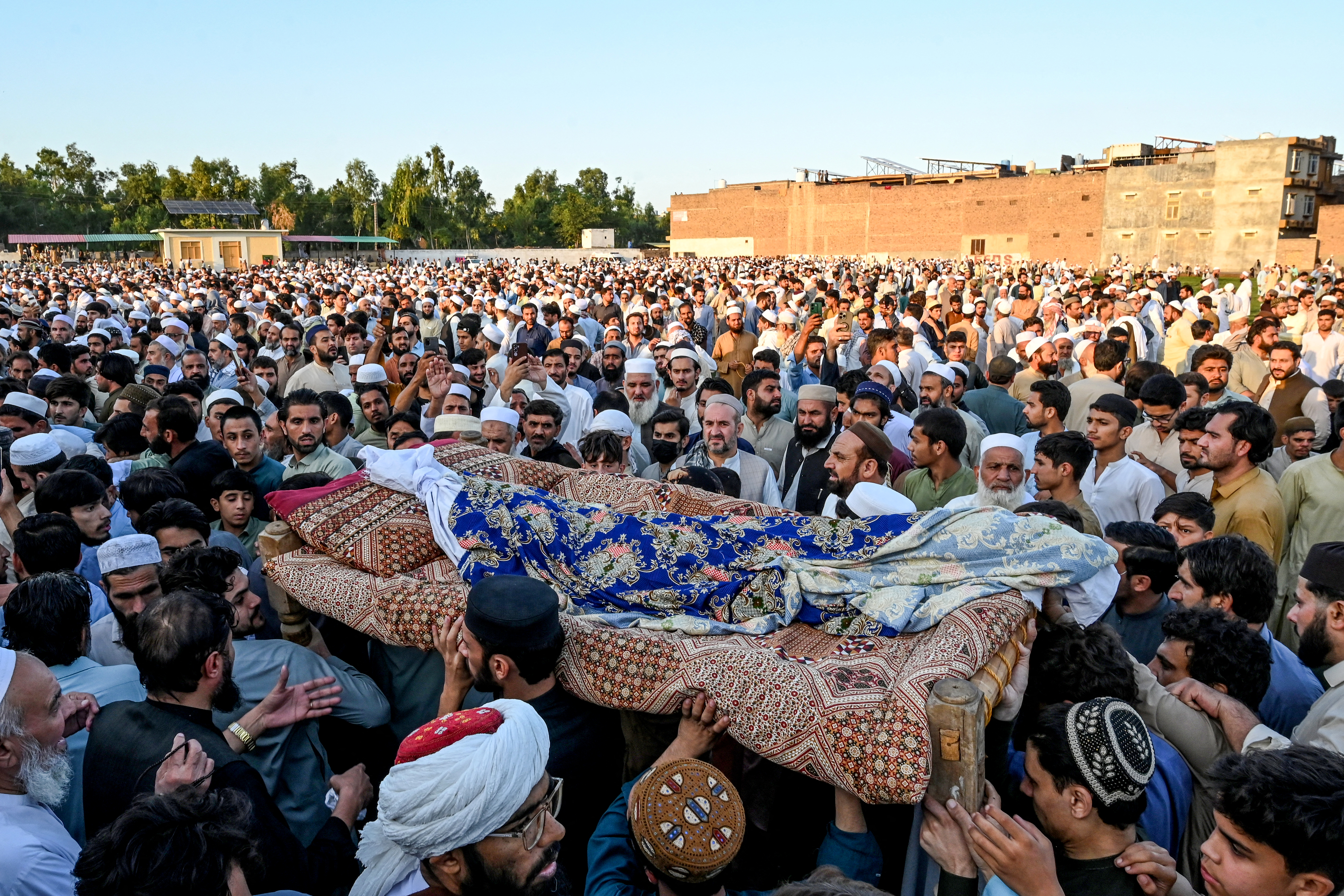 Relatives carry coffins for the funeral prayers of students killed after a roof collapsed at a school in Peshawar on October 15, 2026