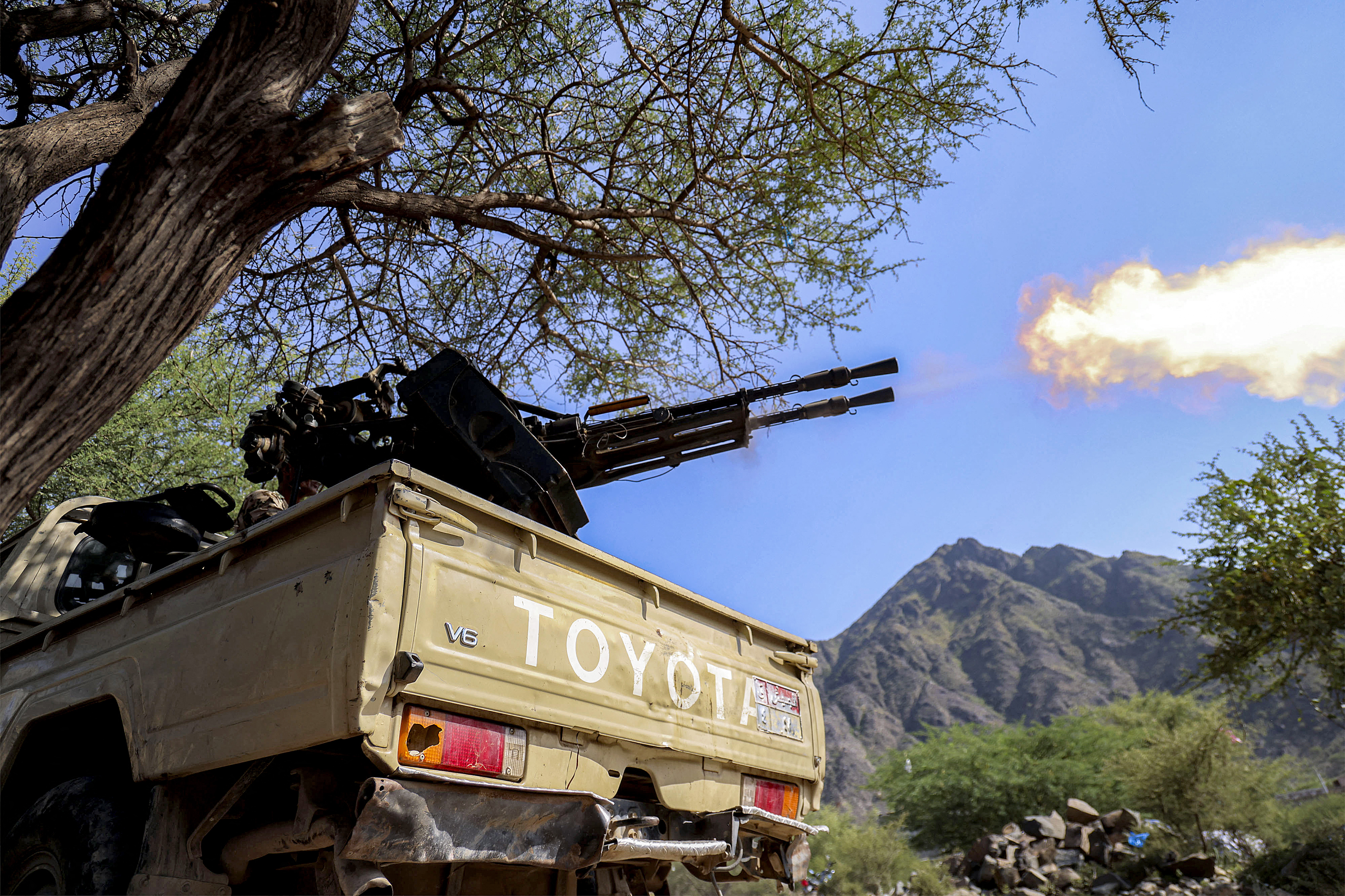 A fighter loyal to Yemen's internationally-recognised government fires a turret from the back of a pickup truck at a position along the frontlines against the Houthis around Mount al-Midan in Yemen's western Taiz province on October 26, 2026.