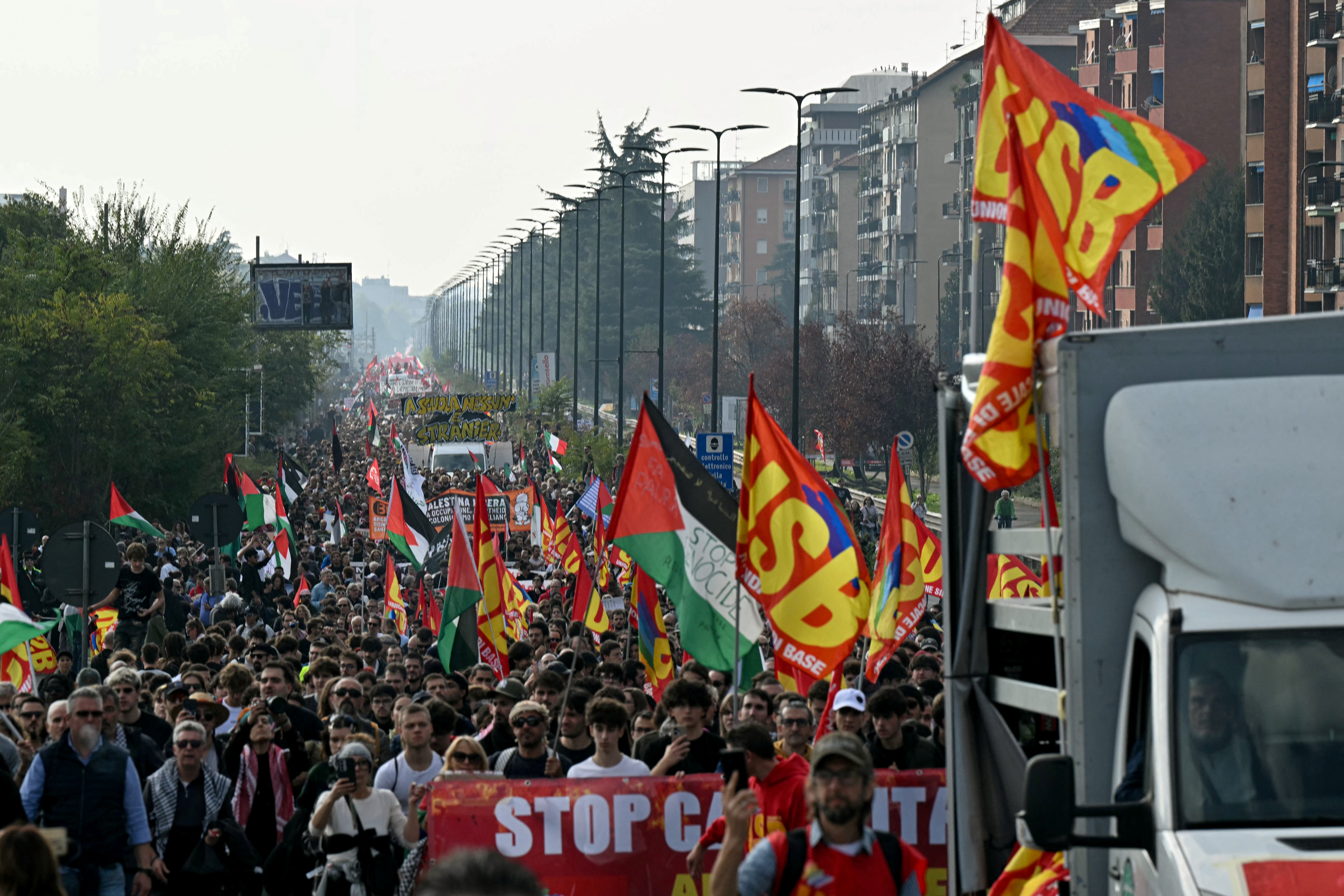 Protesters wave flags of the Unione Sindacale di base as they march during a demonstration part of a nationwide day of strikes and protests as school and university students demand more funding for schools and support for housing, in Milan, northern Italy on October 30, 2026.