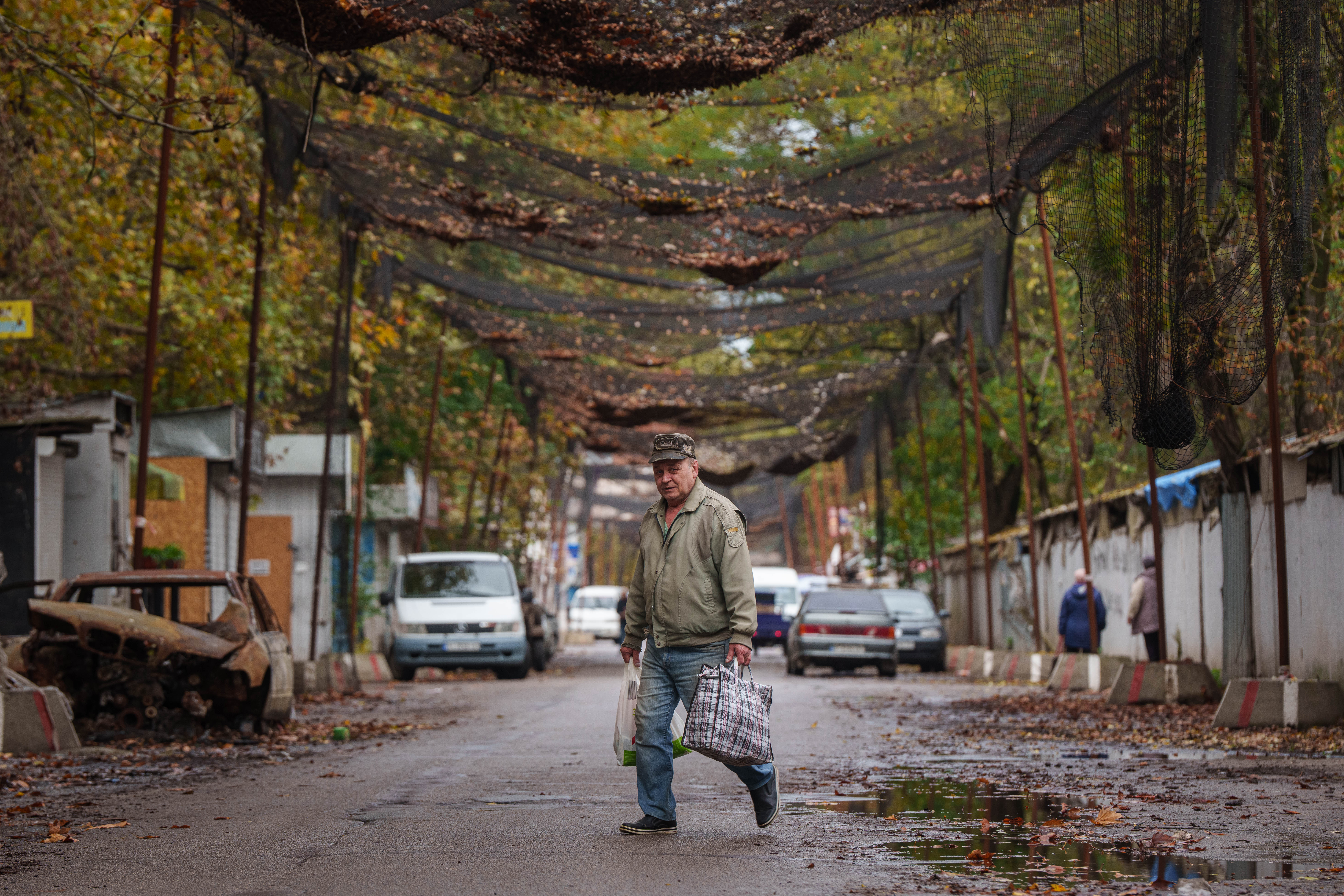 A man walks across a road beneath anti-drone nets stretched over a street during a local ceasefire related to a humanitarian aid mission in Oleshky, in Kherson, Ukraine, Thursday, Oct. 29, 2026. (AP Photo/Evgeniy Maloletka)
