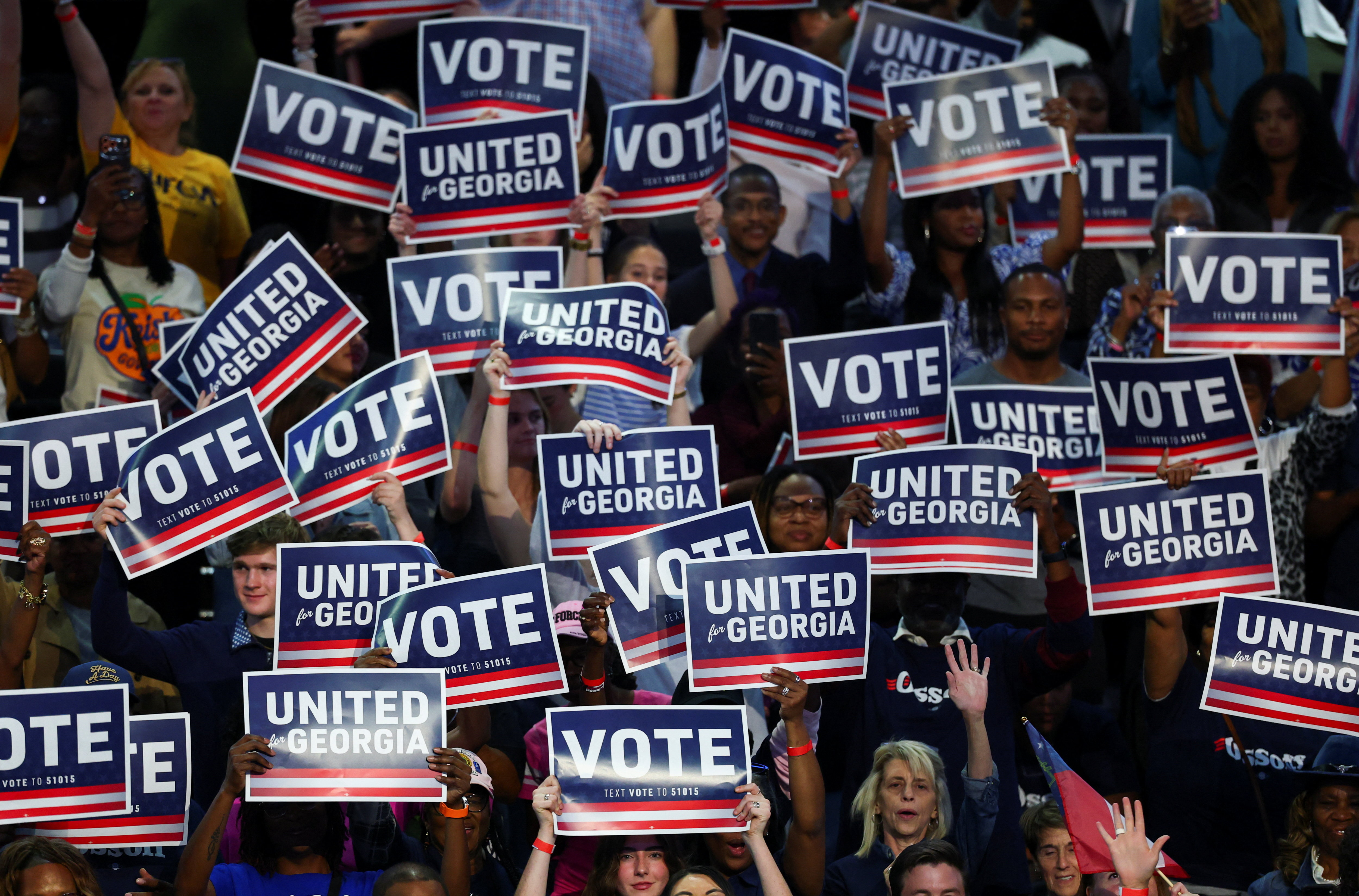 People hold up signs showing their support for former US President Barack Obama, Democratic Senator Jon Ossoff (D-GA) and Democratic gubernatorial nominee Keisha Lance Bottoms at a rally ahead of the midterm elections in Morrow, Georgia, US October 28, 2026. REUTERS/Edgar Su